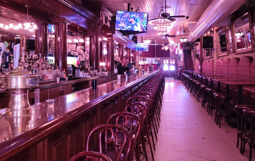 The interior of a restaurant with vintage decor and a long bar stretching into the distance with chairs neatly positioned next to it.