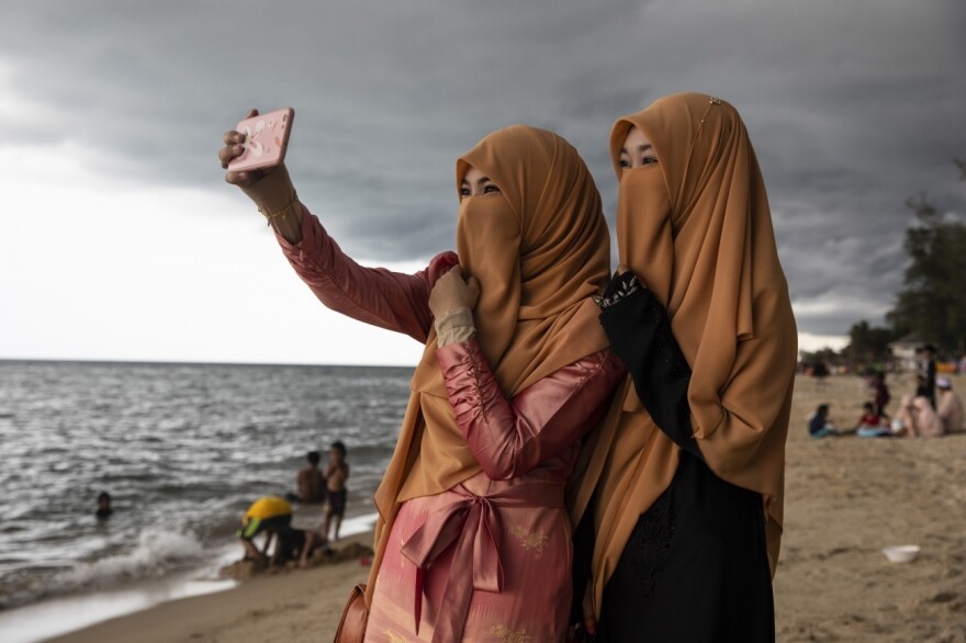 Women take a selfie on the Moslem holiday of Eid al-Fitr on Thailand's Talo Kapo beach.