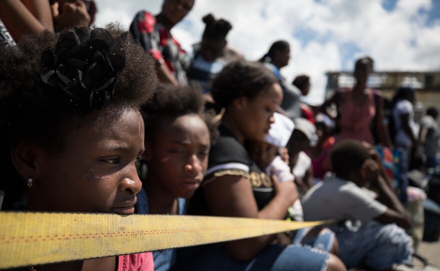 Roselie Petit (right) holds Tristan while she and her other children Laura (left) and Lyana wait at the port of Marsh Harbour, where few buildings were left intact and basic supplies are dwindling.