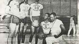 The Purple Knights pose on the court; Harold Sylvester is kneeling next to his coach.