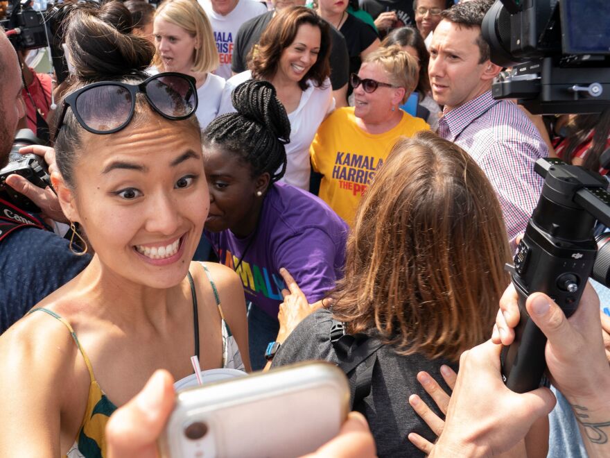 At the 2019 Iowa State Fair, a woman takes a selfie near Sen. Kamala Harris and former Iowa Democratic Party chair Sue Dvorsky.
