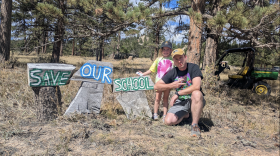 A man and a child stand next to a homemade sign that says "Save Our Schools."