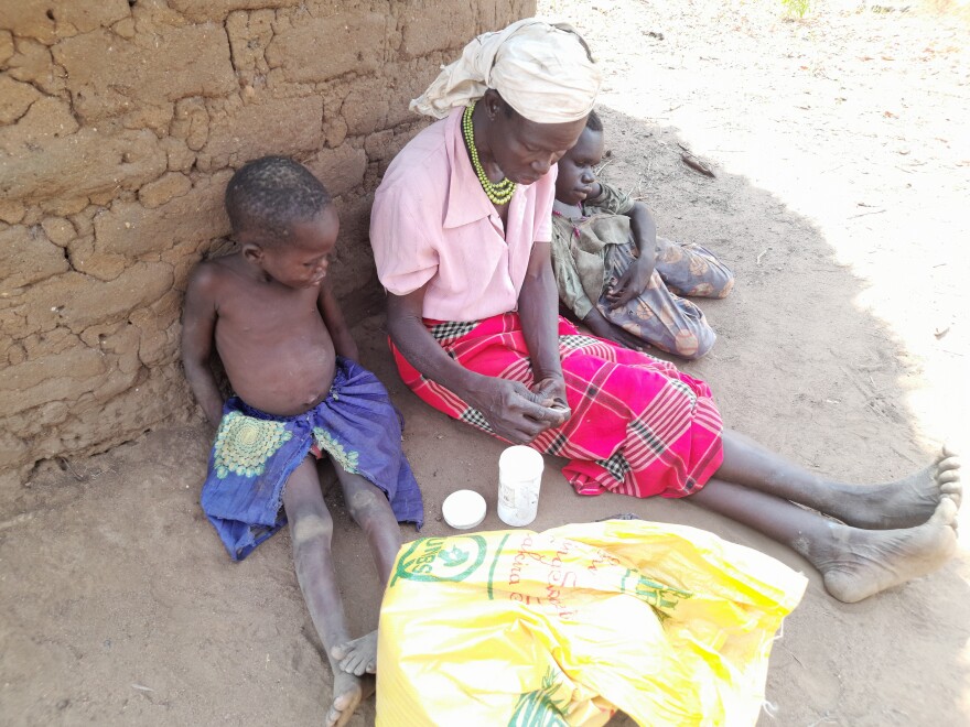 Ventorina Aculu sits next to her granddaughter (left) and youngest son (right). Aculu says that although they take medicine, her two sons with nodding syndrome, both now in their 20s, are not improving.