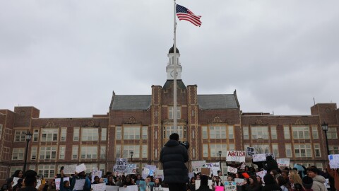 Emmanuel Gutierrez addressed the crowd standing on the school's signage with a megaphone.