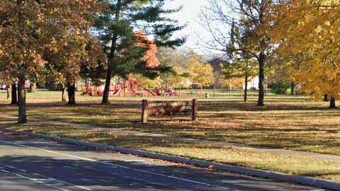 A 2022 image from Google Maps Street View shows the sign for Martin Luther King Jr. Park along MacArthur Highway, with trees and playground equipment in the background.  