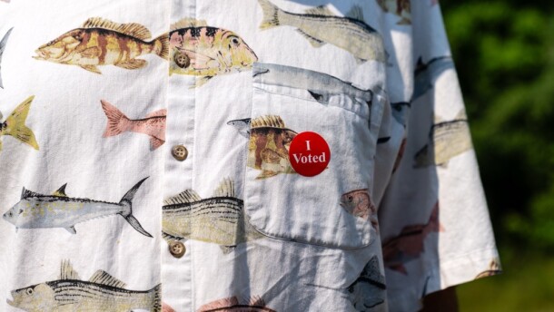 An "I Voted" sticker is placed on the breast pocket of the fish-themed shirt of a voter Aug. 11, 2026, at Woodrow Town Hall in Cass County.