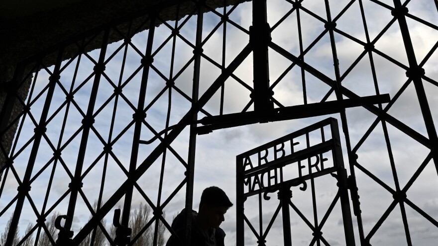 A visitor walks through the entrance gate at the memorial site of the Dachau concentration camp. The inscription <em>Arbeit macht frei </em>means "Work Will Set You Free."