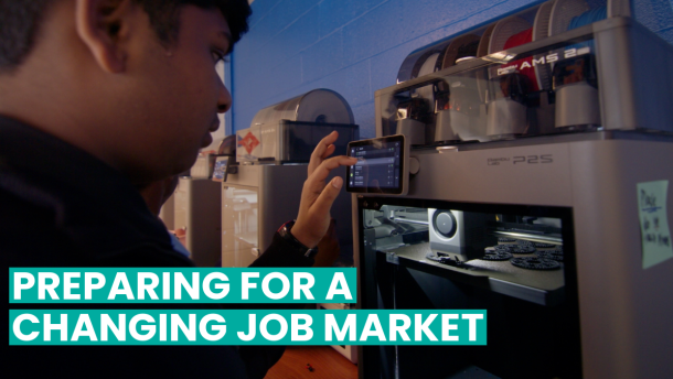 A studen operating a 3D printer with visible printed items inside. A phone is attached to the printer displaying information. Text reads, "Preparing for a Changing Job Market."
