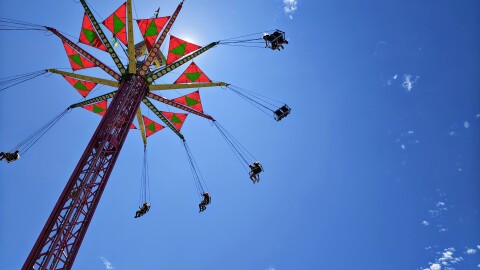 A photo looking up toward a carnival ride which features swings suspended from a tower. 