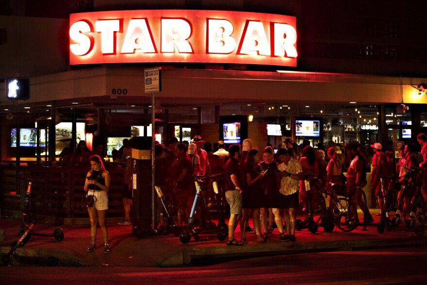 People look down at their phones outside Star Bar 