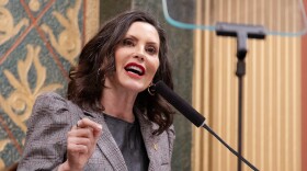 Gov. Gretchen Whitmer stands at a podium in the state capitol.