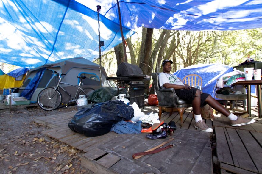 David Cleveland sits outside his tent in Dignity Village near Grace Marketplace Tuesday, March 10, 2015. Cleveland's campsite is located on a 10 acre span of land that the city of Gainesville will lease from the state.