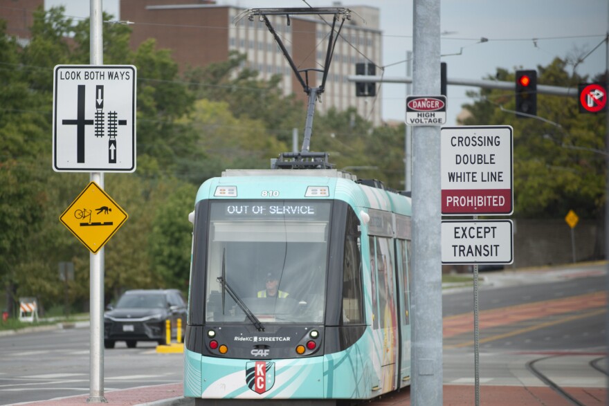 A blue streetcar rides along a street with a lane painted red. Around it are multiple signs telling people to yield to the streetcar and not drive in the transit-only lane.