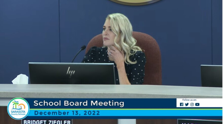 Bridget Ziegler holds his neck and stares left at a school board meeting.