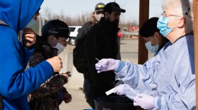 YKHC Nurse Kerry Cobbledick hands out swabs at a station set up for coronavirus testing outside of the Alaska Airlines airport terminal in Bethel, Alaska.