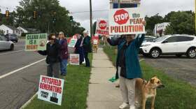 A crowd of people hold signs on a sidewalk