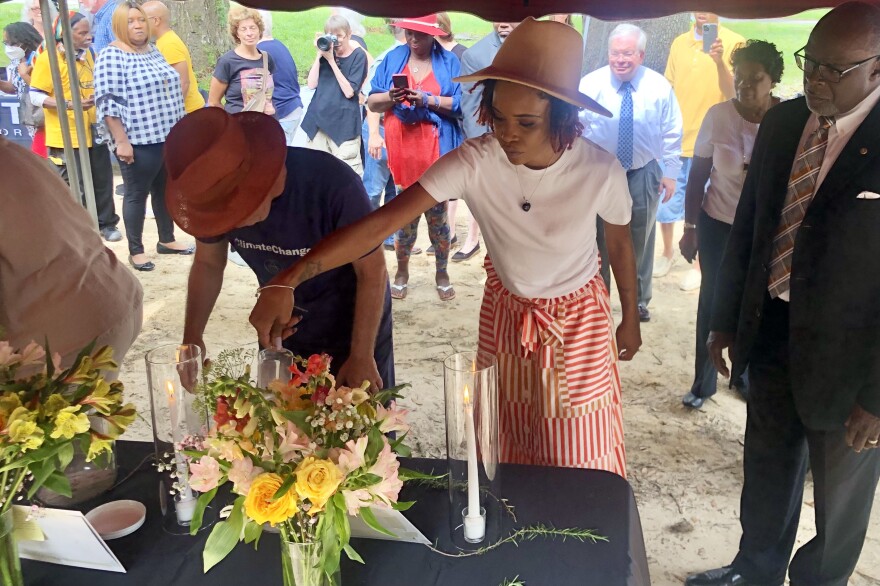 Micanopy Commissioner Jiana Williams pours soil collected from or near the lynching sites into one of the memorial glass jars. (Anissa Dimilta/WUFT News)