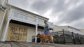 Barbara Timberlake walks with her dog Danny past a boarded up store on the river front in downtown Wilmington, N.C., as Hurricane Florence threatens the coast Thursday, Sept. 13, 2018.