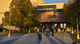 People stand outside of the entrance to a large building.