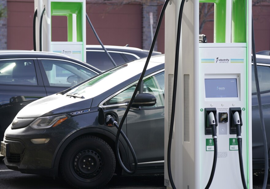 FILE - In this Dec. 21, 2020 file photo, a Chevrolet Bolt charges at an Electrify America site outside Colorado Mills outlet mall in downtown Lakewood, Colo. Electrify America, an electric vehicle charging network funded with money paid by Volkswagen as punishment for its emissions cheating scandal, says it plans to more than double its number of charging stations throughout the United States and Canada. The expansion will include 1,800 fast-charging stations and 10,000 individual chargers by 2025. (AP Photo/David Zalubowski, File)