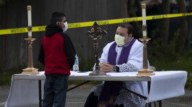 Father Jose Alvarez, right, during walk and drive through confessions on Friday, April 24, 2020, in the parking lot at Holy Family Roman Catholic Church in White Center. 