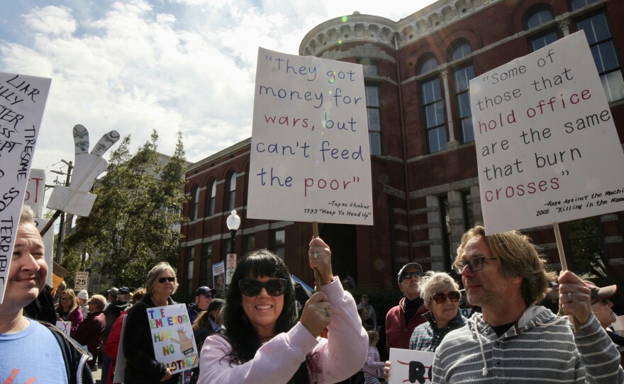Protestors on Princess street holding signs with music lyrics from Tupac Shakur and Rage Against the Machine during the No Kings Protest.