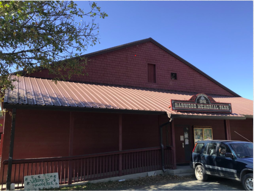A reddish building with a long porch and a sign that says, "Harwood Memorial Park."