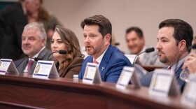 Brown-haired guy in blue suit with other lawmakers. 