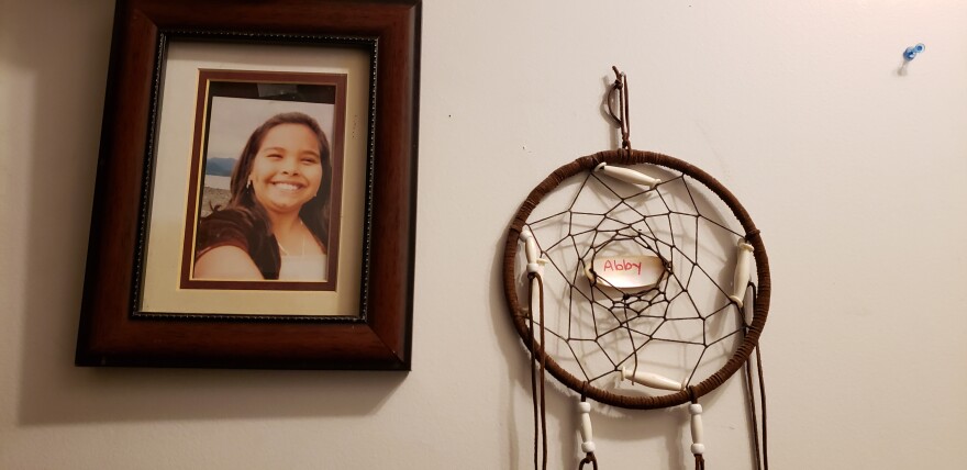 A photo of Abby Kelley and a dreamcatcher hang on a wall in her family’s home in Juneau on Dec. 2. Her parents say that “she had dimples for days.” (Jeremy Hsieh/KTOO)