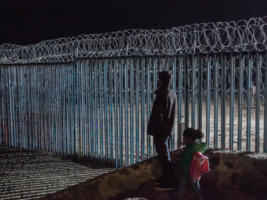 A young man and a little girl look at the border fence from Playas de Tijuana, Mexico. Photojournalist Ariana Drehsler has been covering the caravan of migrants for weeks. In December, Customs and Border Protection agents began pulling her over for questioning each time she crossed back into the U.S.