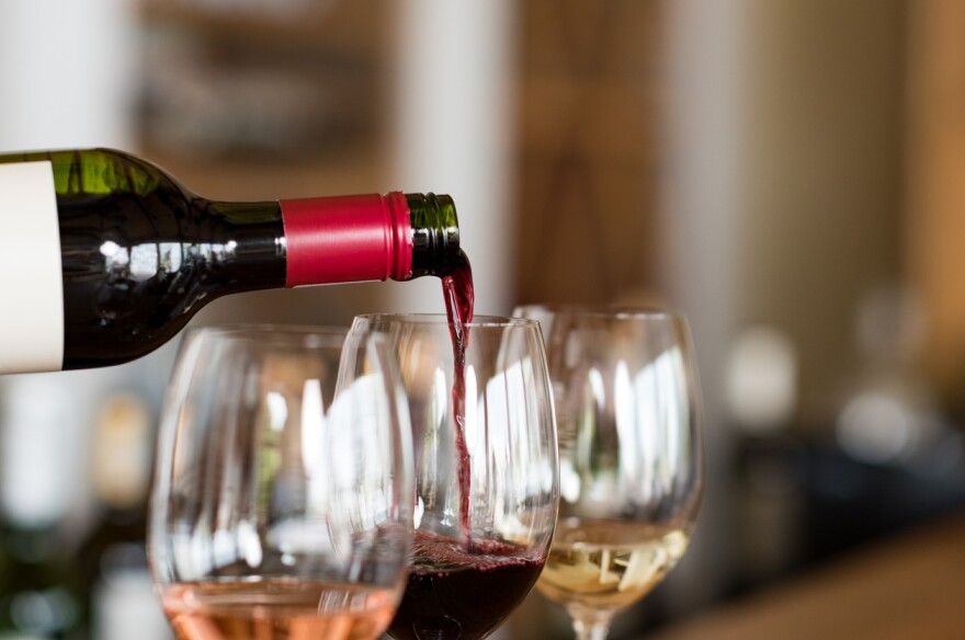 A bottle of wine being poured into a wine glass.