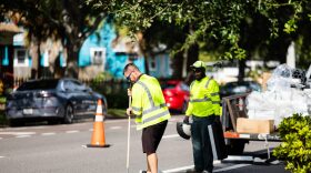 Workers install barrier devices between road and bike lane