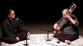 Lee and Whetstone sit on a rug performing their work.