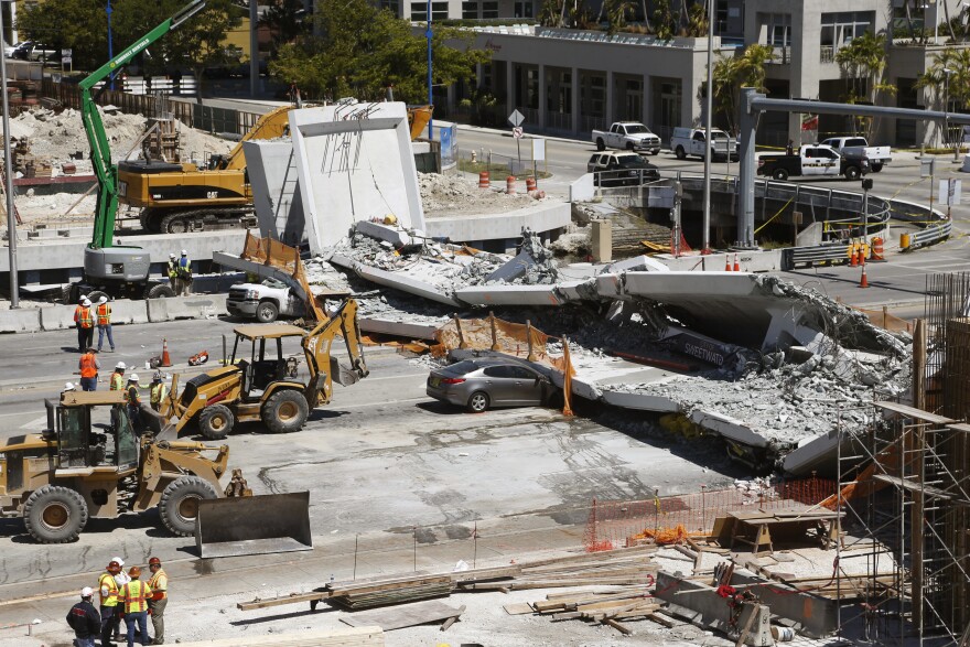 FILE - In this March 16, 2018, file photo, cars are crushed under a section of a collapsed pedestrian bridge near Florida International University in the Miami area. Federal investigators looking into the collapse of the pedestrian bridge that killed six people confirmed they are focusing in part on the emergence of cracks in the structure before the accident. The National Transportation Safety Board on Wednesday, May 23, released a preliminary report light on details but that suggested investigators are focused on cracks found in the south and north ends of the bridge. (AP Photo/Wilfredo Lee, File)