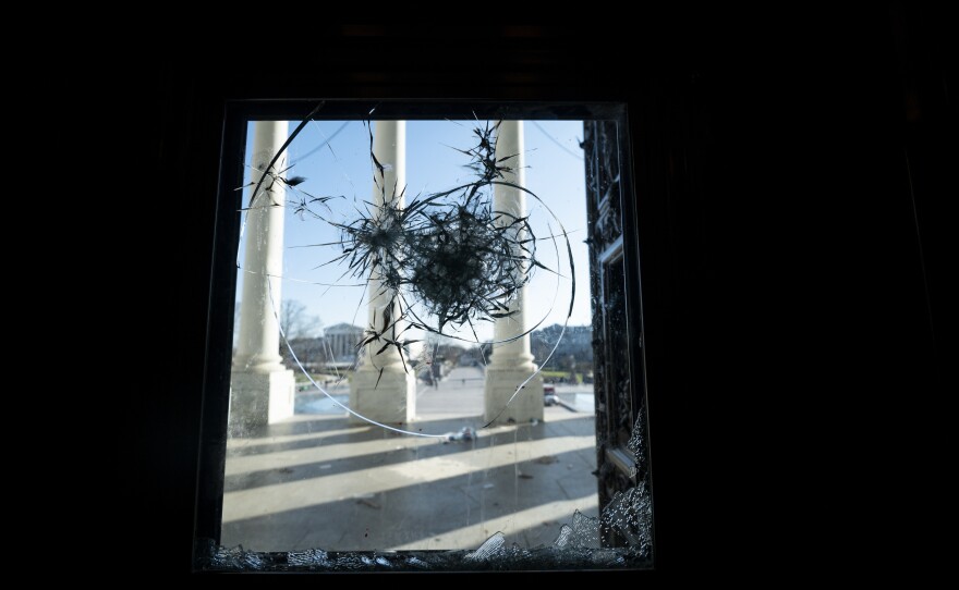 The pillars of the U.S. Capitol are seen through a shattered window on Jan. 7, the day after the riot.
