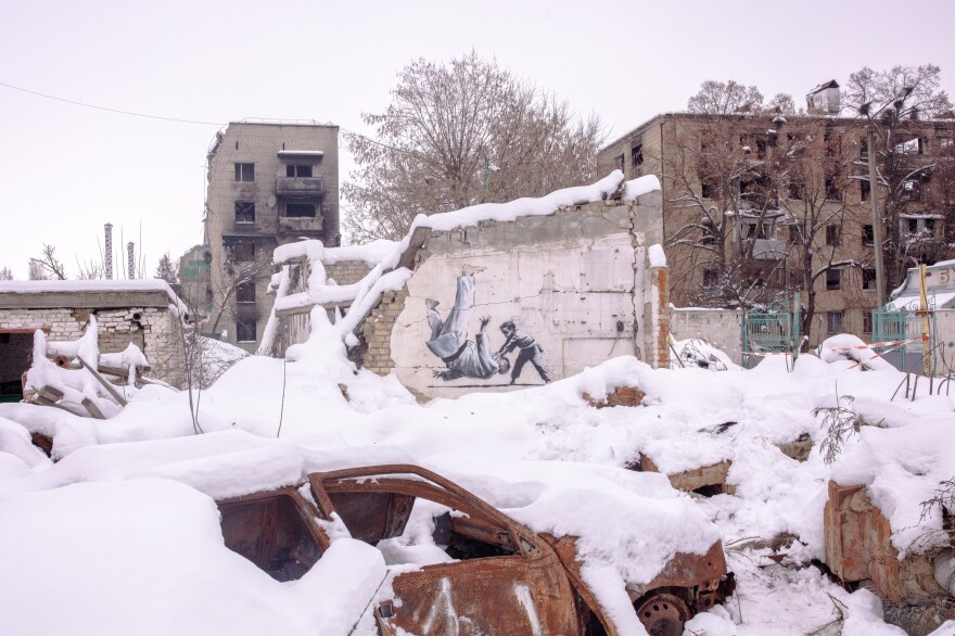 A painting by British street artist Banksy amidst destroyed buildings in Borodianka on Saturday. The image shows a young boy tossing a man to the floor. Both are in martial arts attire. The man is widely assumed to be Russian leader Vladimir Putin, a judo enthusiast.