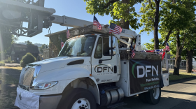 A white bucket truck is shown, with DFN advertised on the side. It is also decorated with mini American flags. 