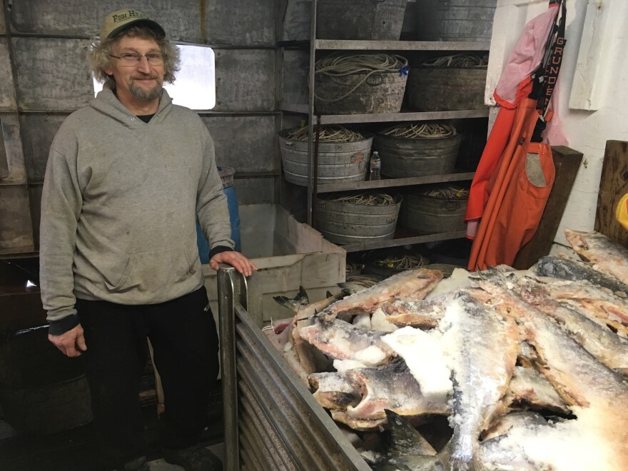 Fisherman Terry Haines next to a container of bait. (Kayla Desroches/KMXT)