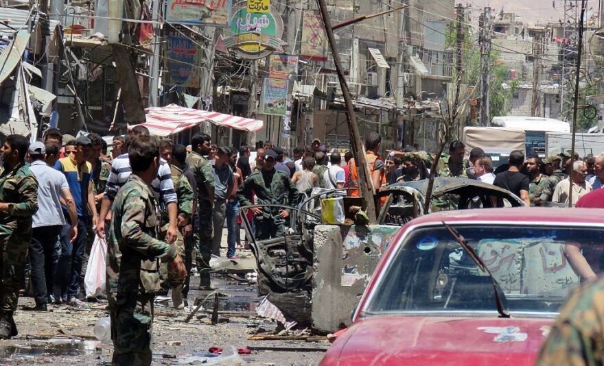 Syrian civilians and soldiers gather at the scene of a double bombing attack on Saturday outside the Sayyida Zeinab shrine, which is revered by Shiites around the world, some 6 miles south of the center of Damascus, state media said.