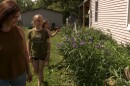 A mother and her two children walk along their garden.