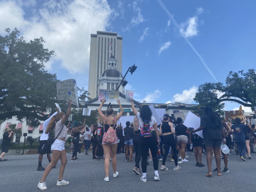 Protesters gather in the intersection of Apalachee Parkway and Monroe Street in downtown Tallahassee Saturday, in front of the Old Capitol building.