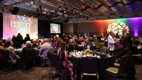 Tulsa community members sit at their tables within the Arvest Convention Center as they await their dinner.