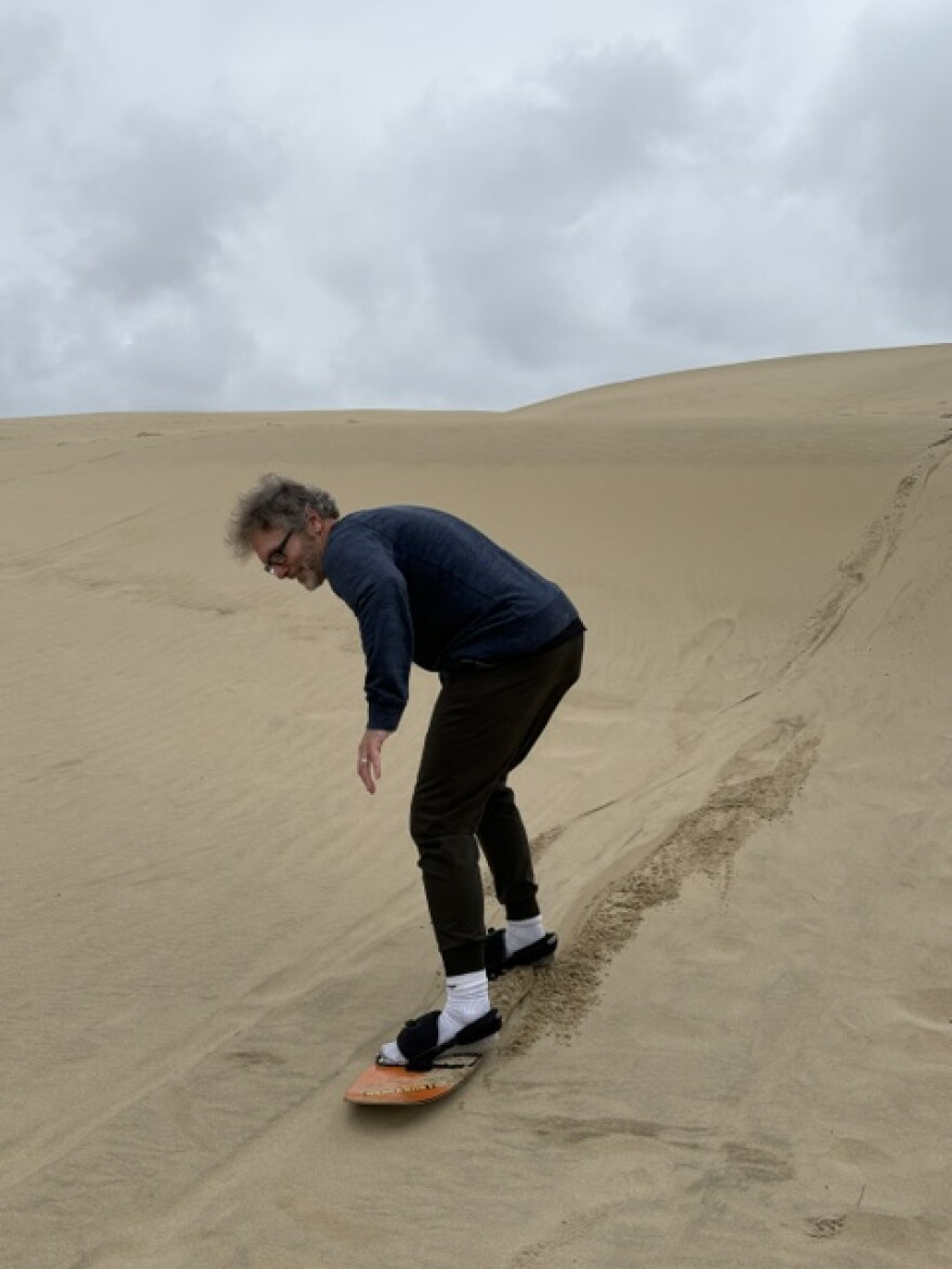 The host, inching toward the edge of the dune