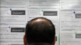 A job seeker looks at listings on a bulletin board.