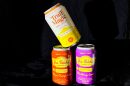 Three cans of THC-infused drinks are stacked on one another in front of a black background.