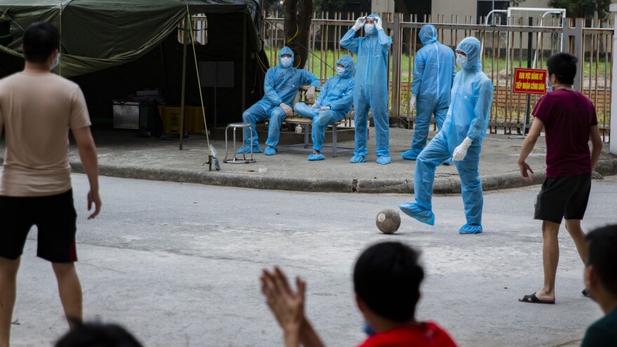 A health worker plays goalkeeper in a pick-up soccer game with quarantined residents, who make an effort to maintain an appropriate distance from each other as they play.<strong></strong>