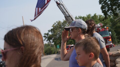 A woman salutes during a procession for firefighters who died battling wildfires near the Colorado-Utah border in Grand Junction, Colo., June 29, 2026.