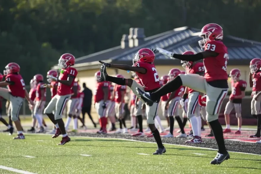 Football players from a Mississippi high school warm up before practice. There are new recommendations to get big linemen safe during hot weather workouts.