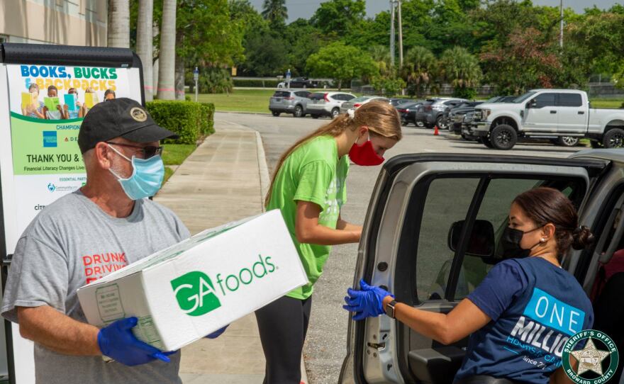 Volunteers pass out food at a drop-off event.