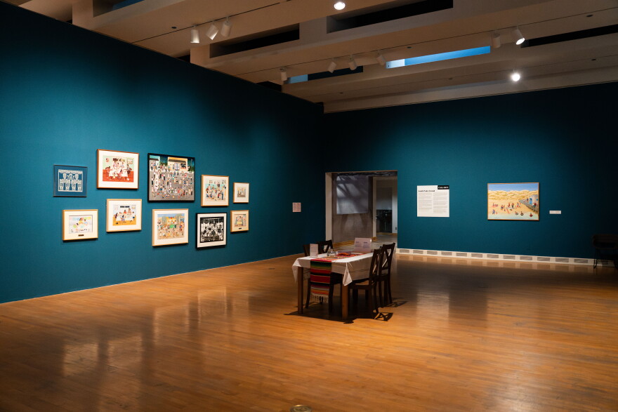 room with wood floor and blue walls, table in the middle and art hanging on the walls